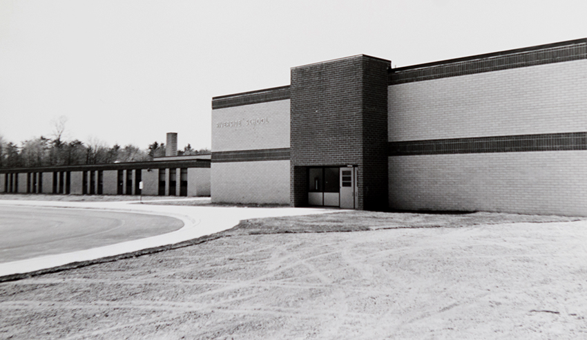 Black and white photograph of the front of Riverside Elementary School facing Old Mount Vernon Road taken in 1968. The picture was taken during the fall because in the distance some of the trees have started to lose their leaves. The grounds in front of the building are still being sodded. 