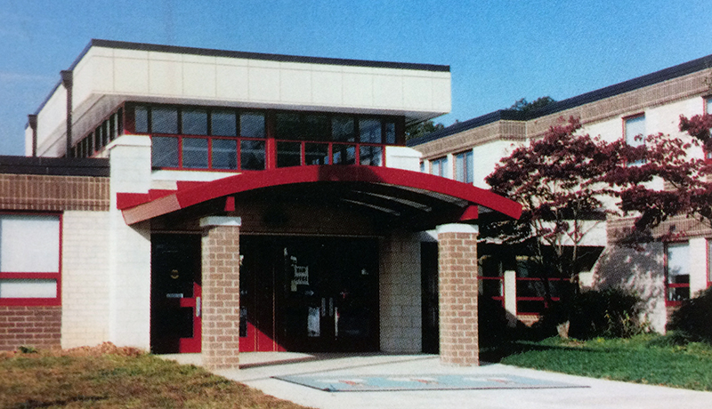 Color photograph of the main entrance to Riverside Elementary School from our 2004 to 2005 yearbook. The school has been newly renovated and the entrance awning is painted a bright red. 
